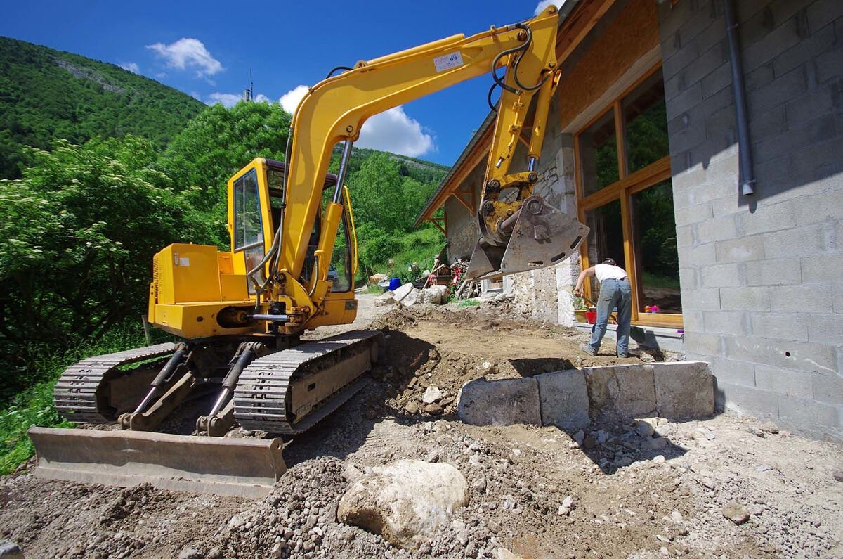 pelleteuse qui réalise le terrassement d'un jardin d'une maison