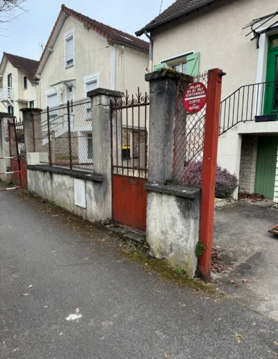 Vieux mur de clôture délabré avec portail rouillé et piliers en béton fissurés à Rambouillet avant rénovation