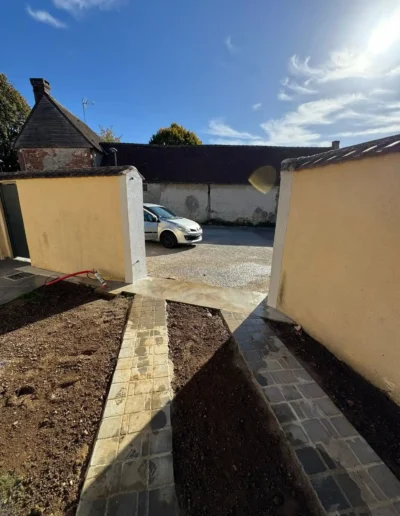 Maçonnerie paysagère et préparation du sol avec bandes de roulage pour entrée de maison